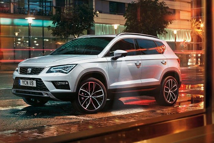En silverfärgad Seat Ateca parkerad i en stadsmiljö på kvällen.